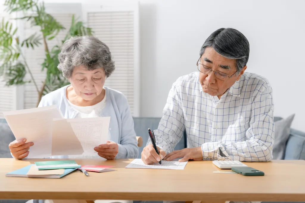デイサービスの費用に関する書類を確認する高齢の夫婦