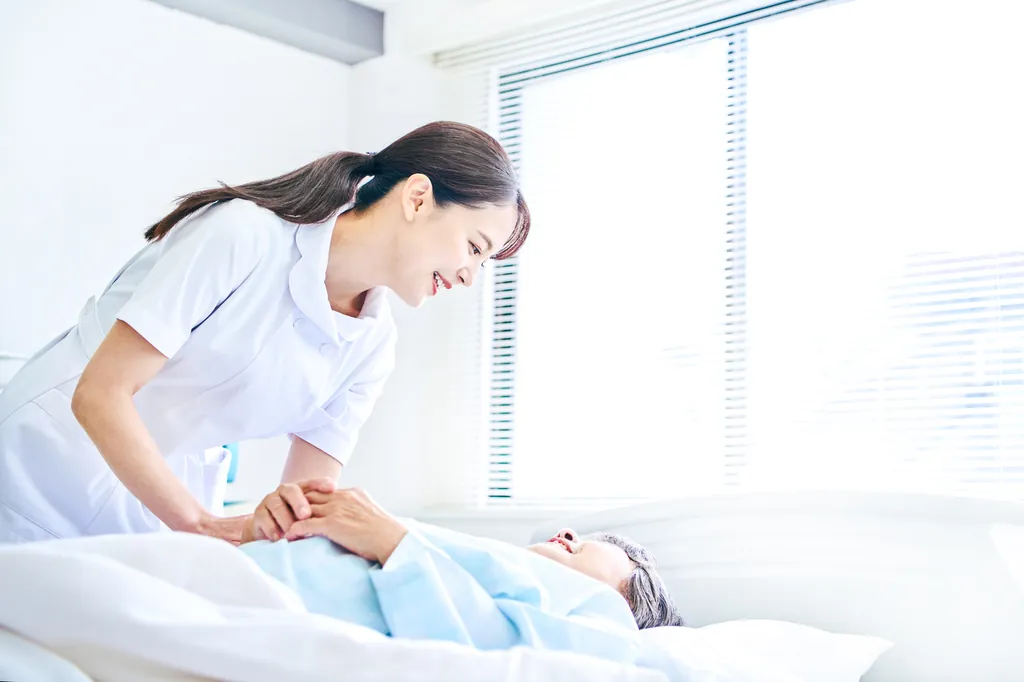 看護師が利用者の手に触れながら体調を確認している様子