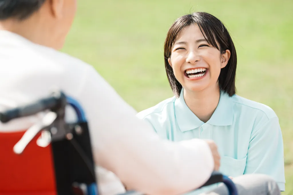 看護師が車いすの高齢者と笑顔で話している様子